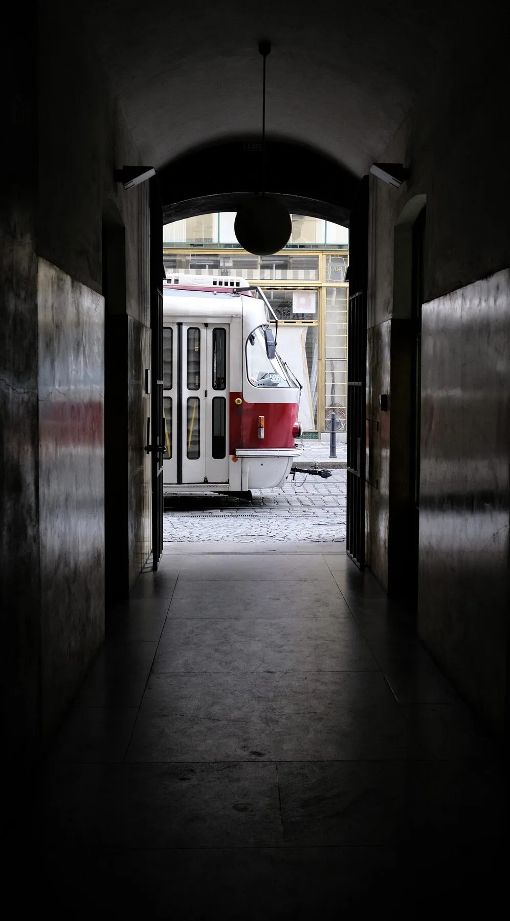 A dark archway frames a red-and-white tram.