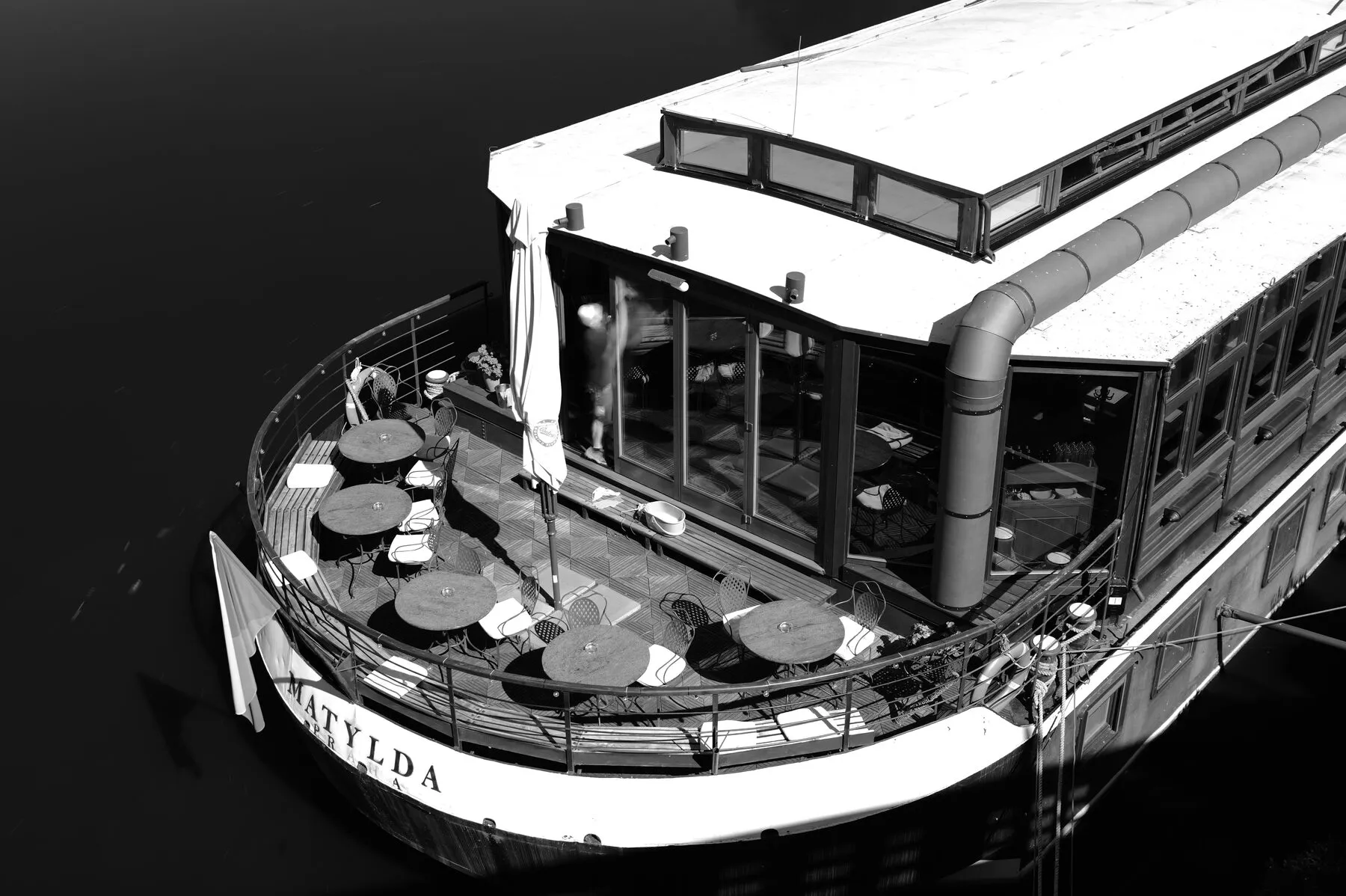 The parasol-dotted bow of a moored river boat on black water.