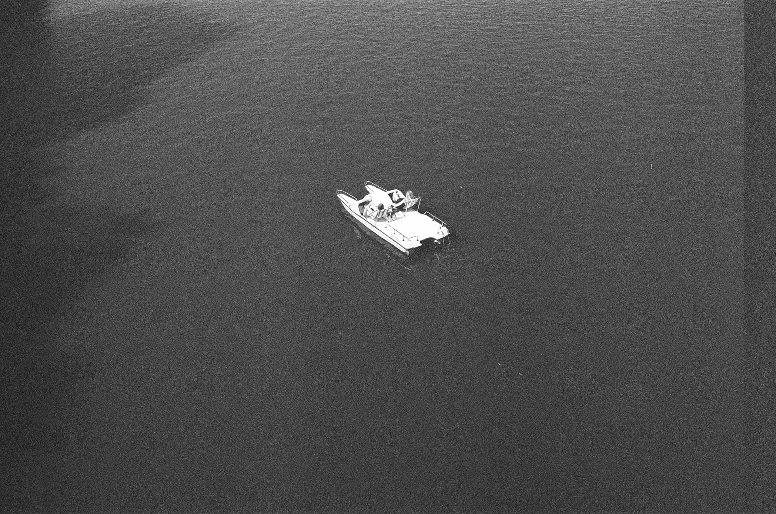 One small motorboat alone on a wide field of grainy dark water.