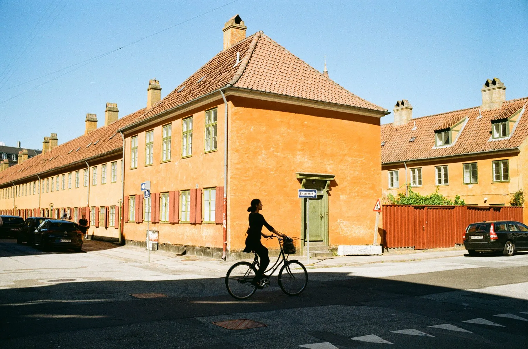 A cyclist passes the corner of the ochre Nyboder row houses.