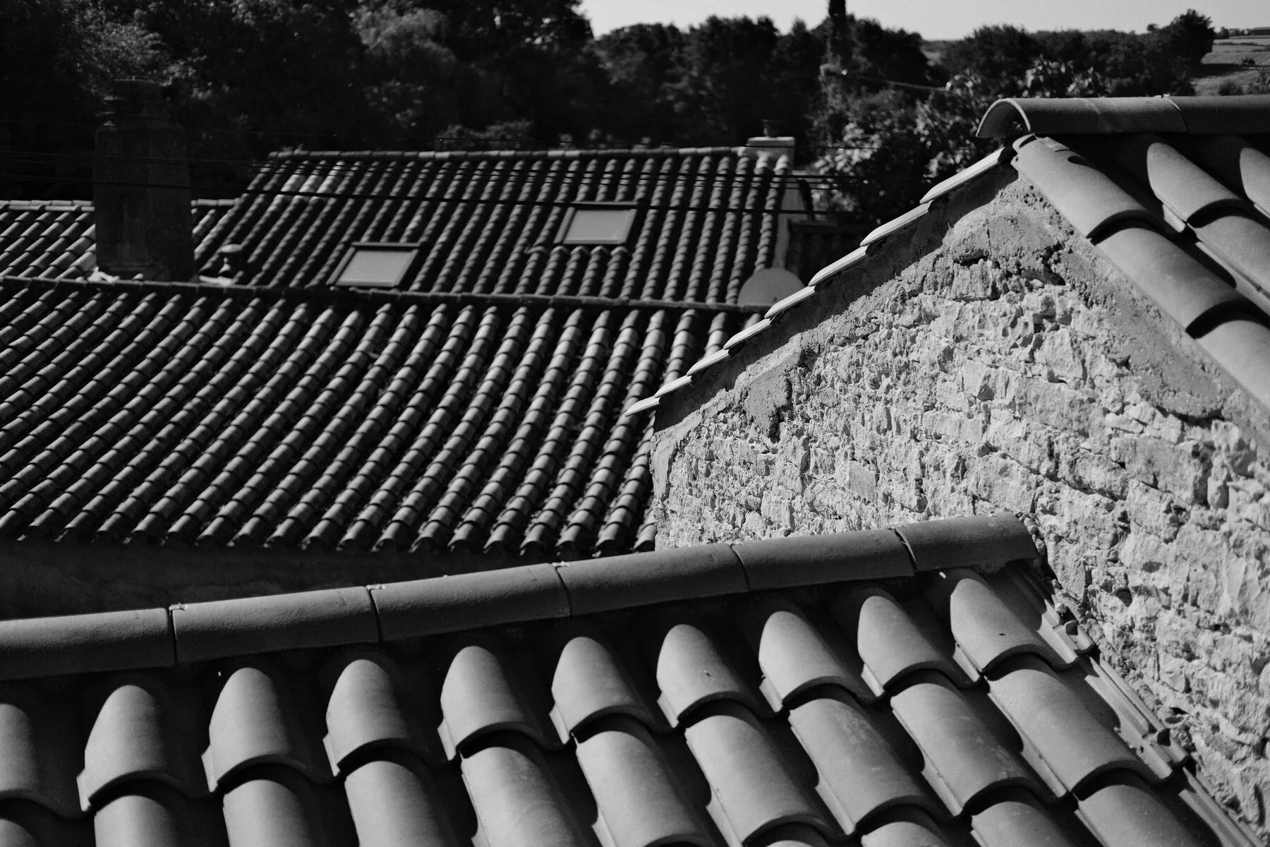Layered terracotta roof tiles meeting a rough stone gable.