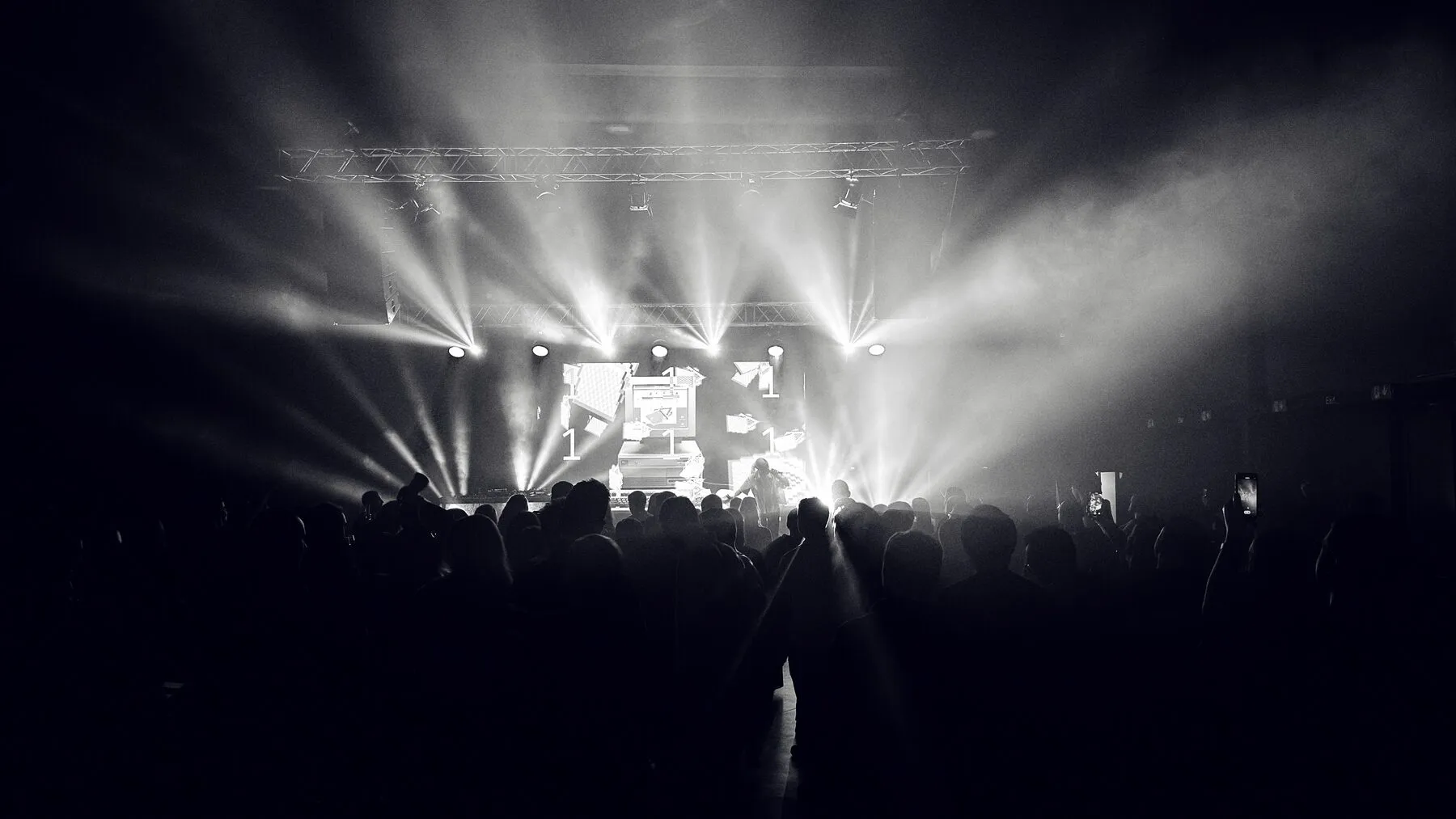 Stage-light beams over a crowd of silhouettes.