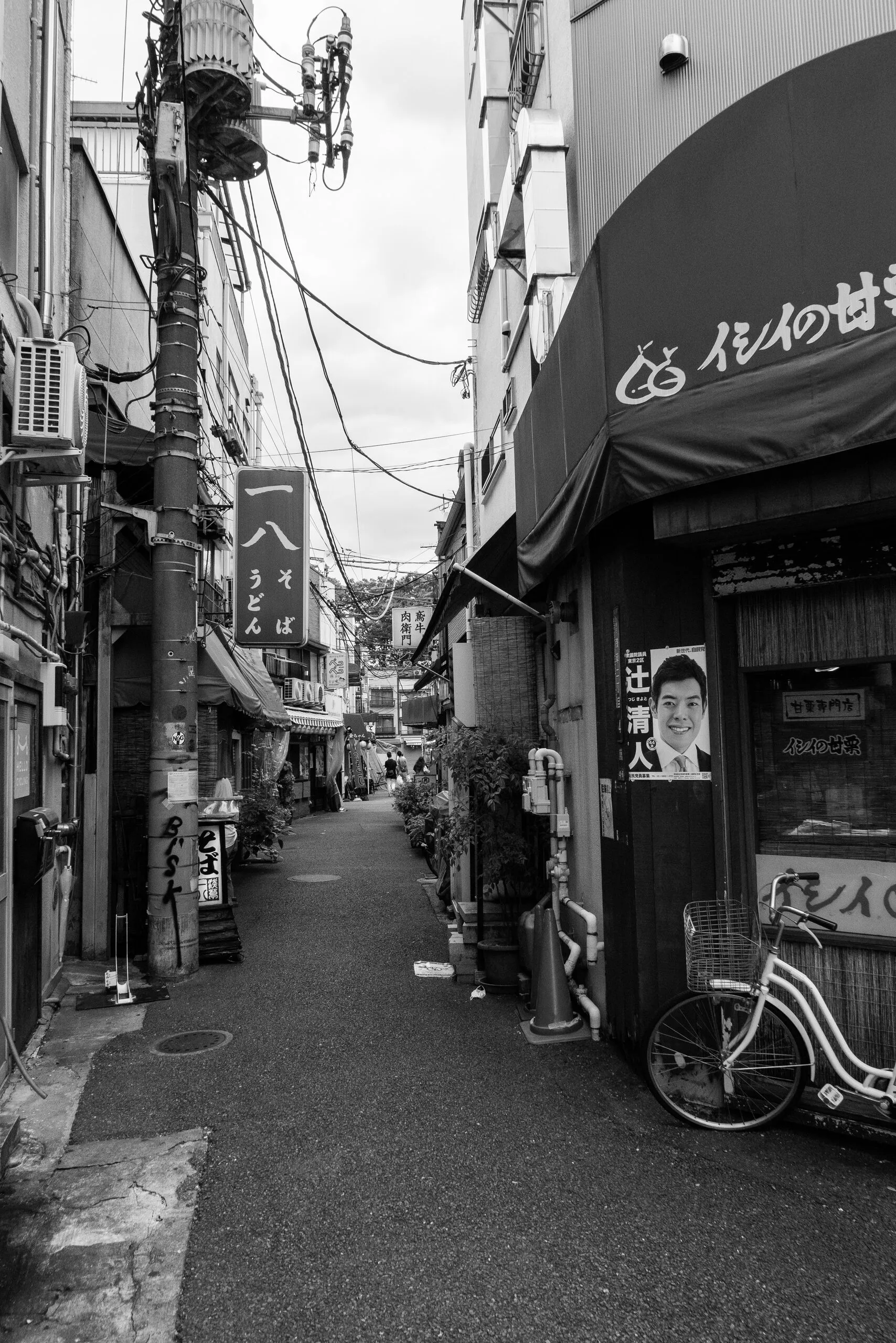 A narrow alley with an udon sign and a single bicycle.