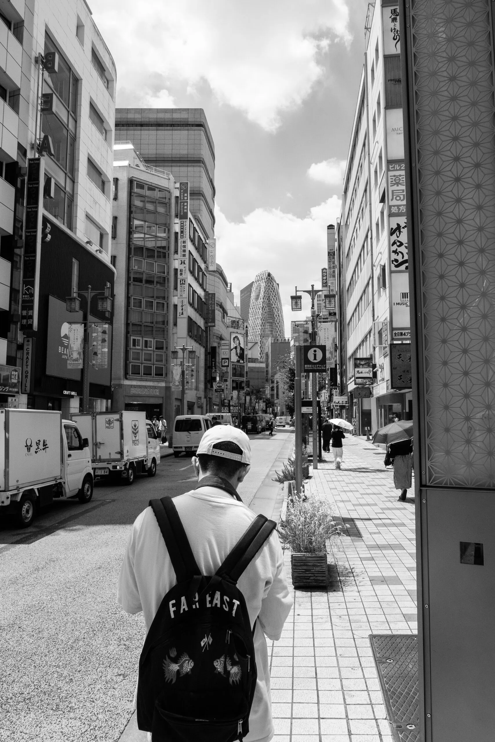 A man from behind, 'FAR EAST' on his backpack, bright sky.
