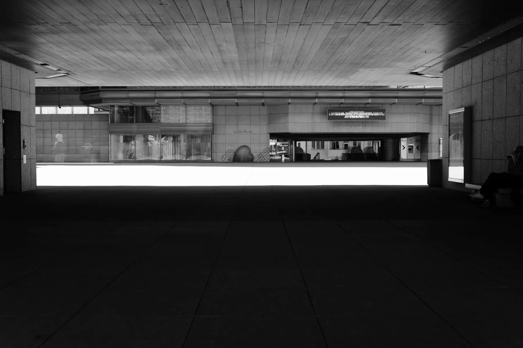 A band of blown-out light between the dark slab and floor of a Prague underpass